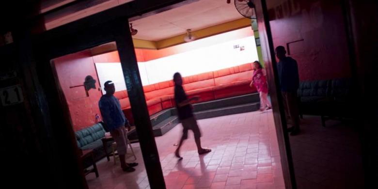 Pekerja seks dan penjaga berada di toko mereka yang tutup di kawasan Dolly, Surabaya, Rabu (18/6/2014) malam, setelah pemerintah kota resmi menutup kawasan prostitusi terbesar di Asia Tenggara tersebut. AFP PHOTO / ROMEO GACAD 