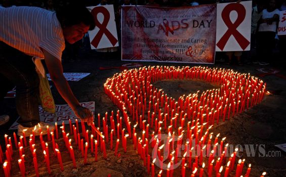 Seorang aktivis AIDS meletakan lilin pada sekelompok lilin yang menyala membentuk lambang pita merah AIDS selama acara menandai Hari AIDS Dunia di Manila, Philipina. Sabtu (1/12/2012) Diskriminasi terhadap kaum homoseksual dan orang yang terinfeksi HIV berkontribusi terhadap peningkatan pesat dari penyakit yang tak tersembuhkan di Filipina, pejabat dan aktivis kesehatan mengatakan. (AFP PHOTO / TED Aljibe) 