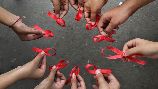 Activists of a non-governmental organization display red ribbons, symbol of HIV-AIDS awareness, as they pose for photographers during an awareness campaign on World AIDS Day, in a business district of Bangalore, India, Sunday, Dec. 1, 2013. (AP / Aijaz Rahi)